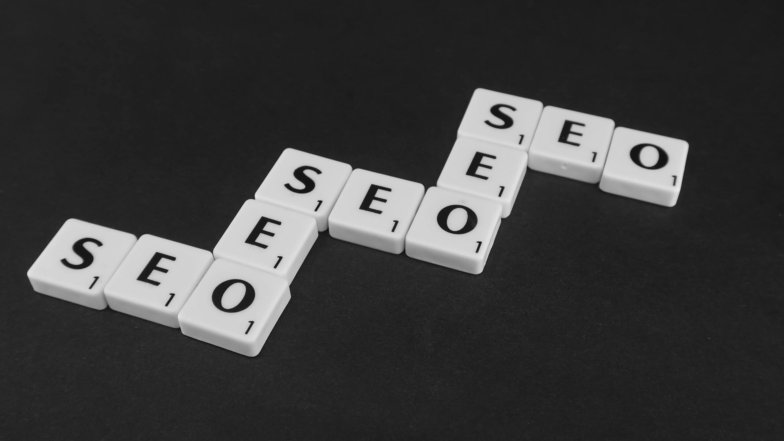 SEO spelled with Scrabble tiles on a black surface, representing search engine optimization concepts.